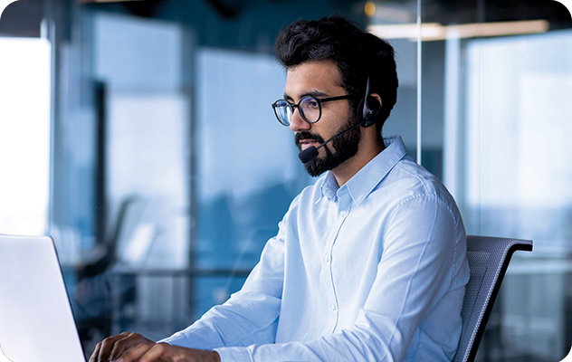 A picture of a male over the phone interpreter wearing a headset and typing something on his laptop.