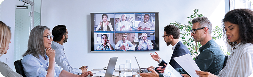 A picture of a business team meeting in person and virtually in a big conference room