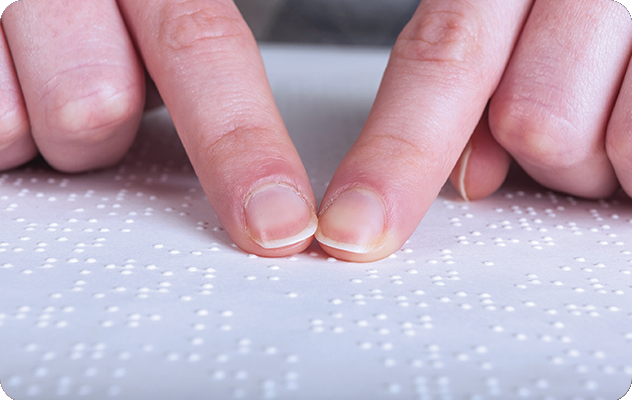 A picture of two fingers reading braille on a page for braille transcription services.