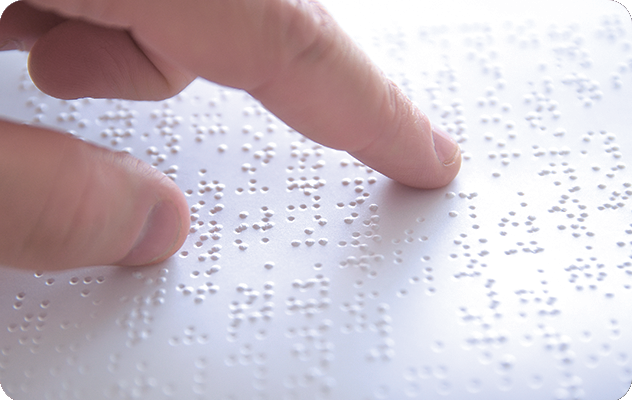 A picture of fingers reading braille pages, which iTi can help transcribe and translate.