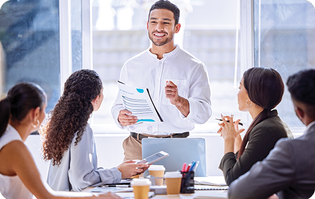 A picture of a young man presenting language services in a conference room while four employees watch him present.