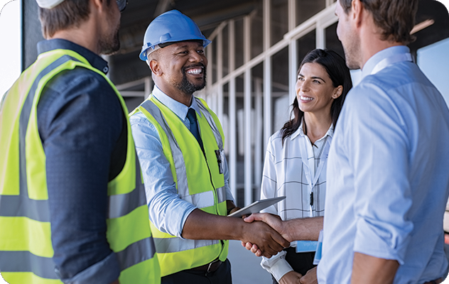 A picture of a man in a safety vest with a hard hat shaking hands with a business man and an interpreter