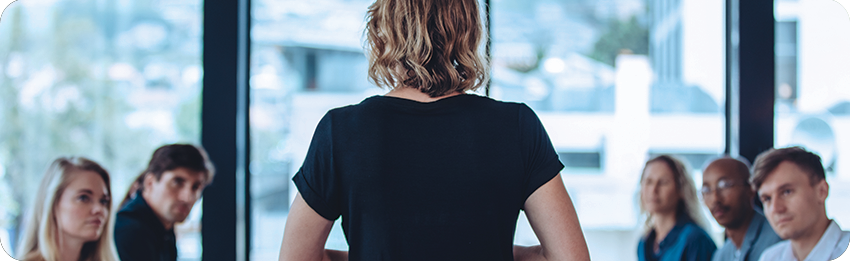 A picture of the back of a woman as she gets ready to present to the team in a conference room