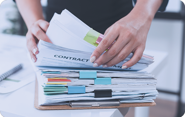 A picture of a woman's hands sorting through paper documents including contracts to be included in document translation services.