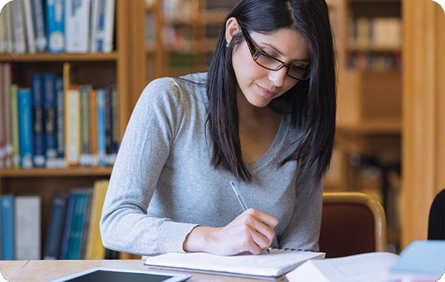 A picture of a young woman translating academic materials in a library.