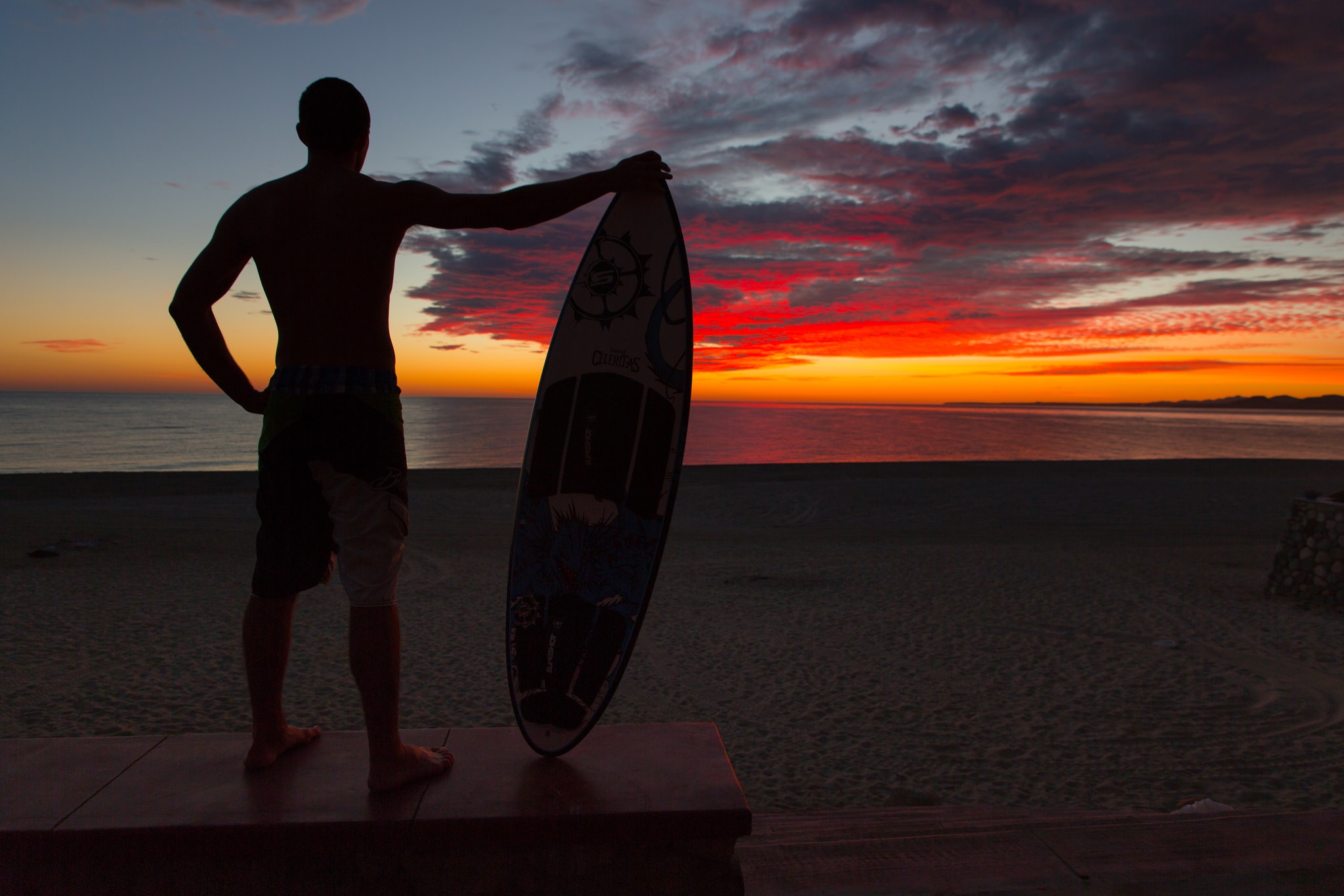 Surfer on beach at sunset in Mexico