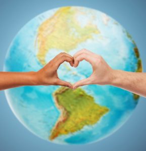 Global community. Human hands forming a heart over the globe