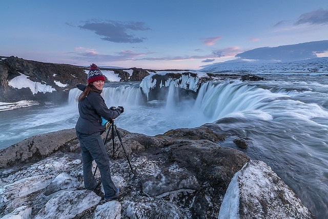 Women taking a photo of a waterfall in winter