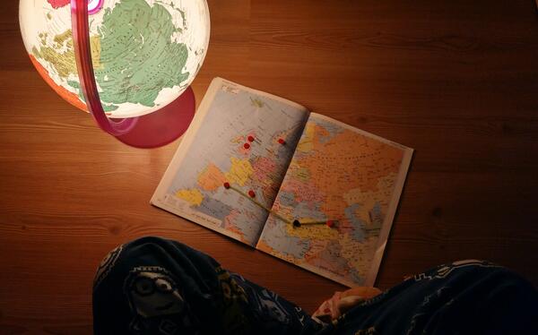Person sitting on the floor looking at a map and a globe