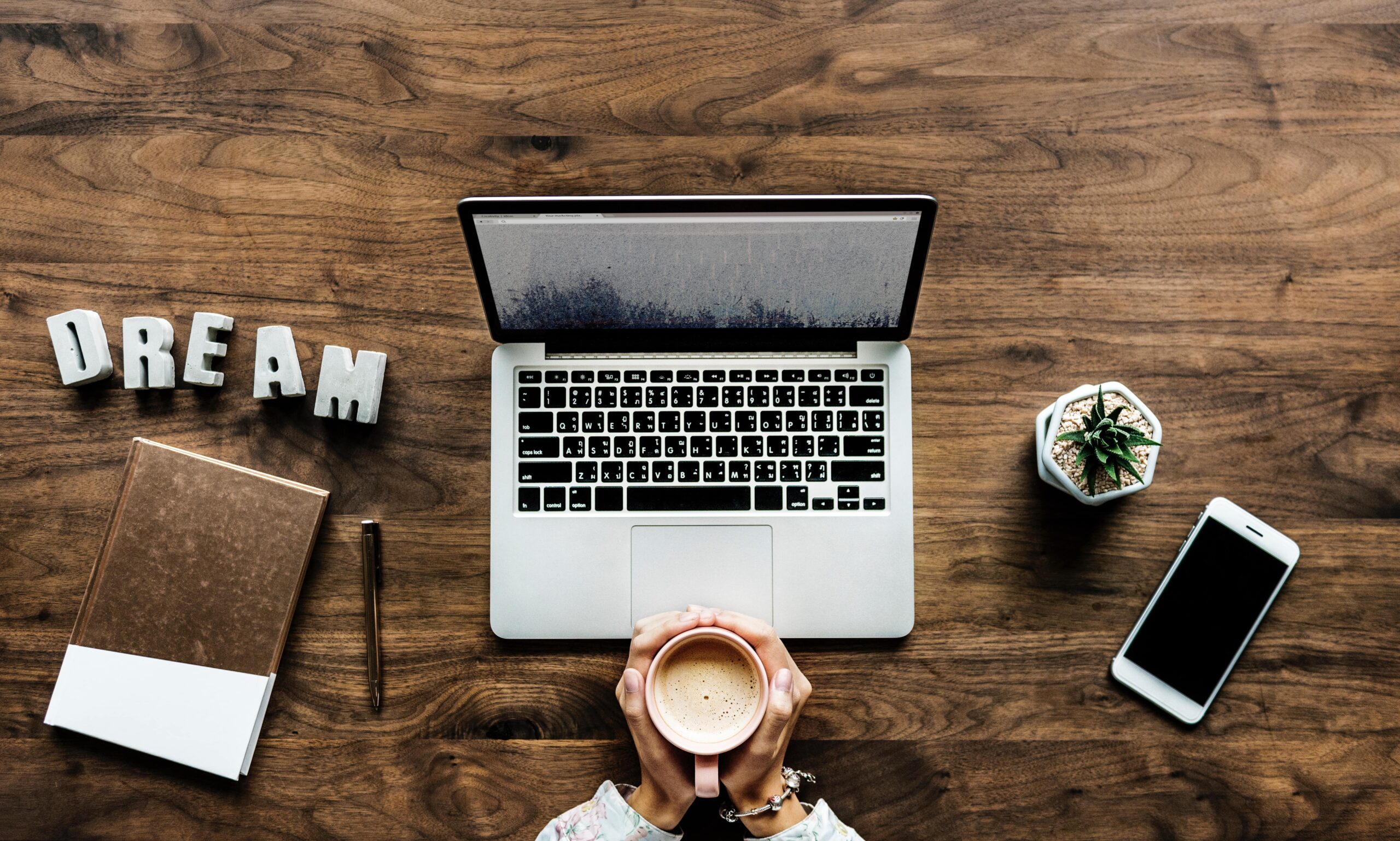 Translator sitting at a table with coffee in hands in front of laptop