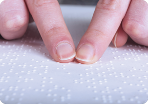 A picture of two fingers reading braille on a page. iTi offers braille transcription services.