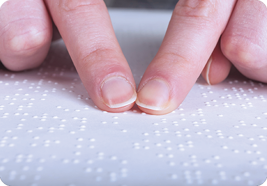 A picture of two fingers reading braille on a page. iTi offers braille transcription services.