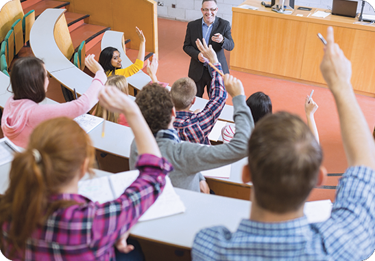 A picture of student raising their hands for a professor in a lecture hall. iTi provides language services for schools and colleges.