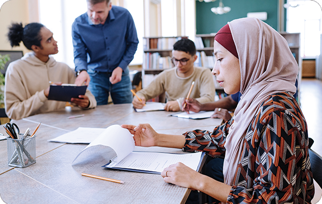 A picture of a teacher giving one on one instruction to students whose second language is english.