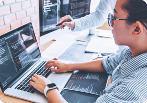 A picture of a woman typing on a laptop at her desk working on a website for localization services