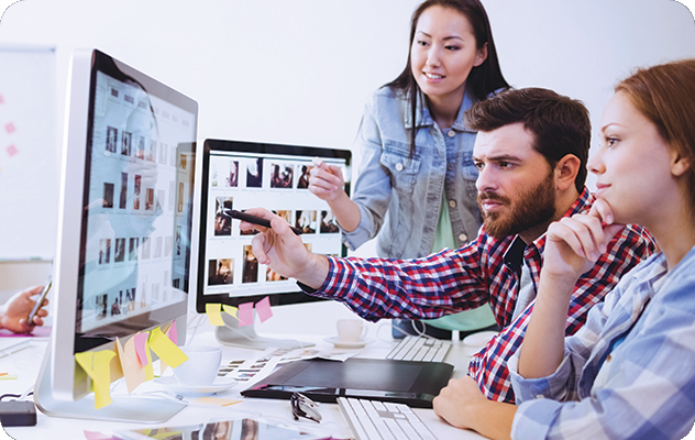 A picture of a team reviewing images on a desktop computer during multilingual desktop publishing services